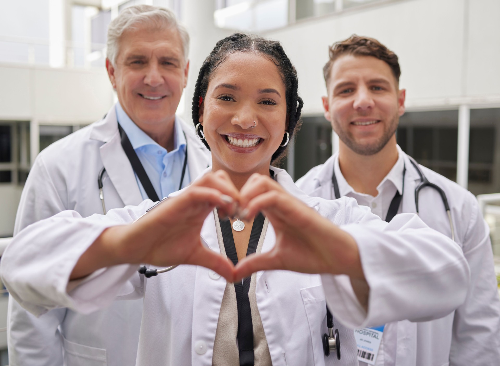 Mano de corazón, doctora y retrato con un equipo de atención médica y bienestar en un hospital. Felicidad, amor y emoji gesto con las manos con médicos en una clínica médica mostrando solidaridad y atención comunitaria